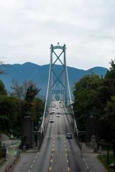 View of traffic on Lions Gate Bridge in Vancouver, BC, with scenic mountain background.
