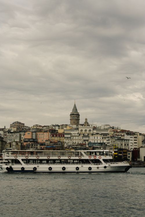 Free A cloudy day view of Istanbul with Galata Tower and a ferry on the waters, showcasing urban architecture. Stock Photo