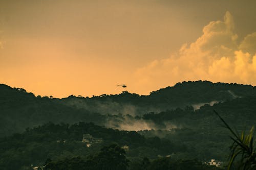 Silhouette of Chopper Flying Over the Mountain