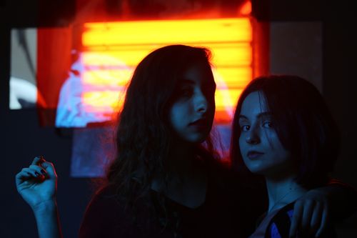 Free Artistic portrait of two young women with dramatic neon lighting indoors. Stock Photo