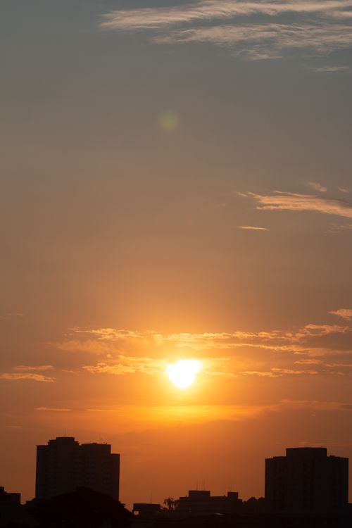 Free Silhouetted cityscape at golden hour with a dramatic sunset sky. Stock Photo