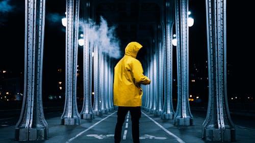 Back View of a Person in Yellow Jacket Standing on the Bicycle Lane