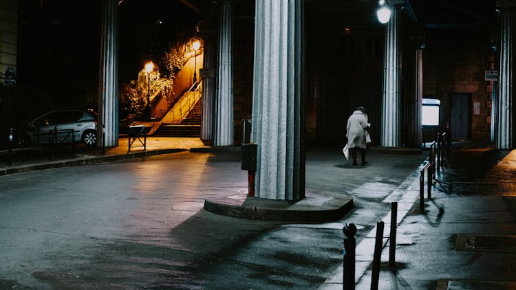 Person Walking On Sidewalk At Night