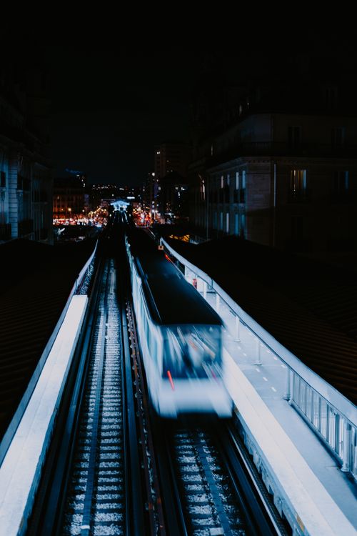 Free Long exposure of a fast train on city tracks at night, showcasing speed and illumination. Stock Photo