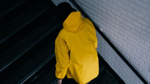 Free Person in a yellow jacket walking up concrete stairs in an urban setting. Stock Photo