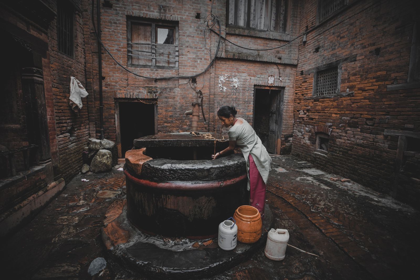A rural Indian woman draws water from a village well at dawn