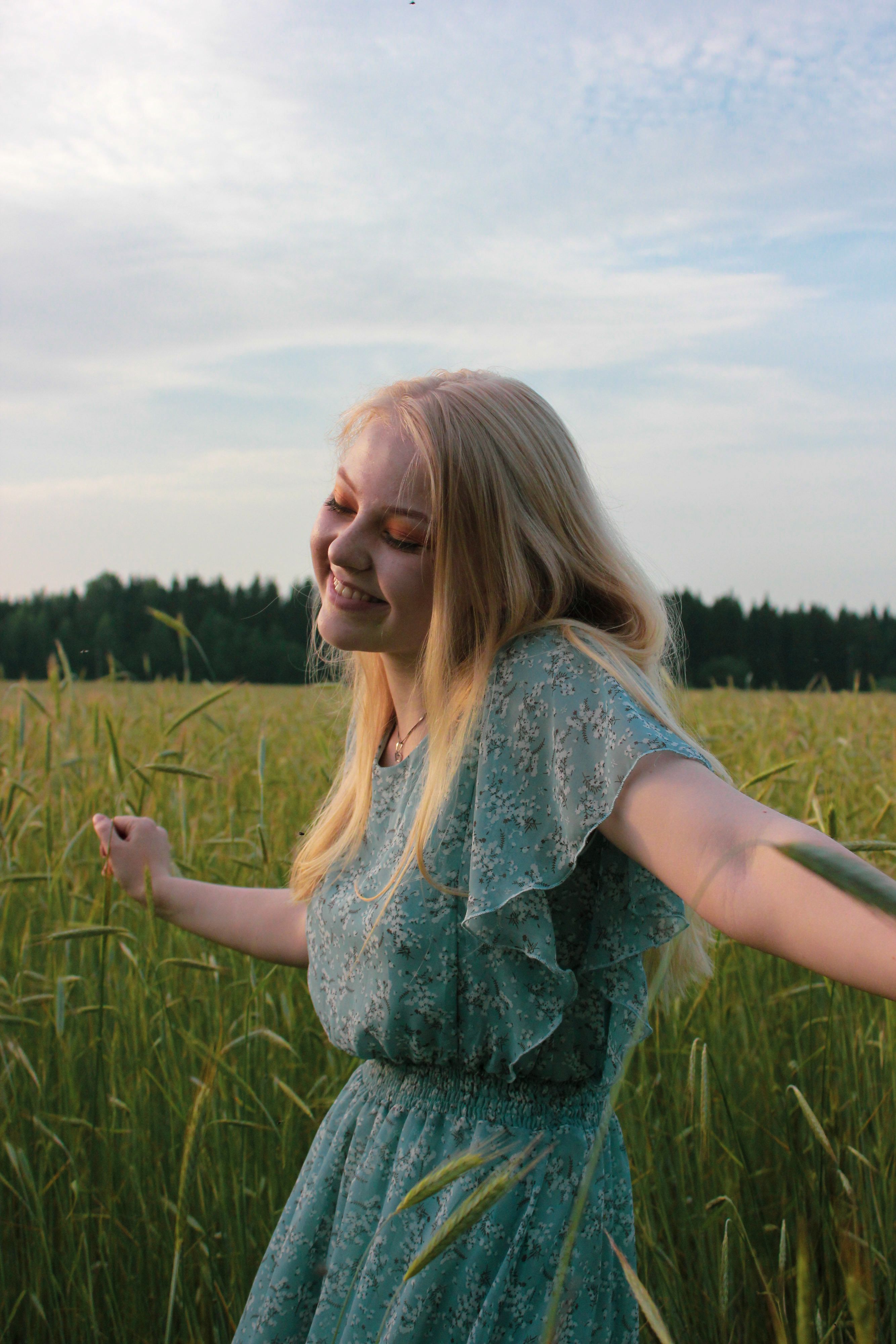 A young woman enjoying a peaceful summer day in a lush wheat field, embracing nature.