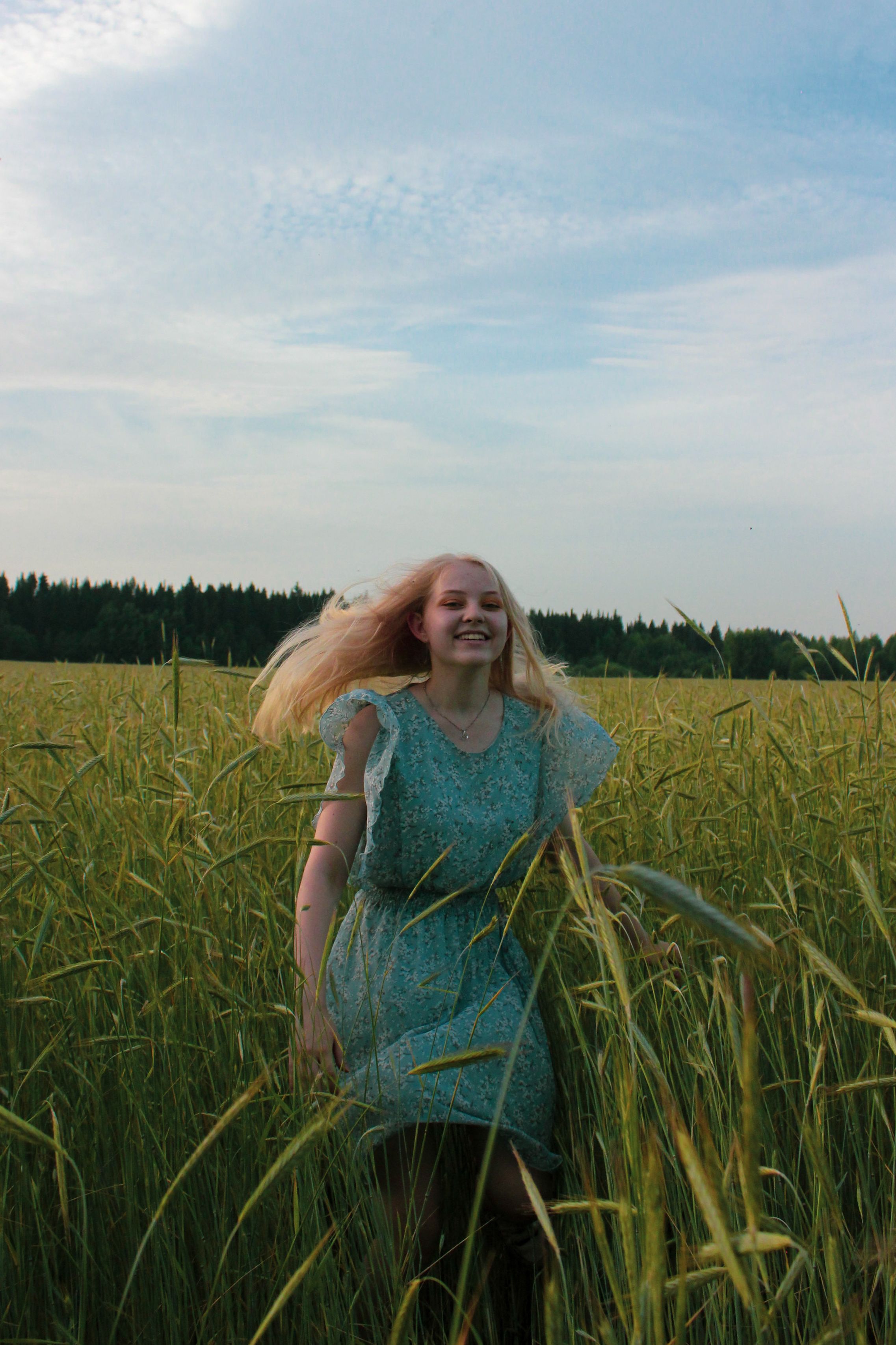 A young woman joyfully runs through a sunlit field, embracing nature and freedom.