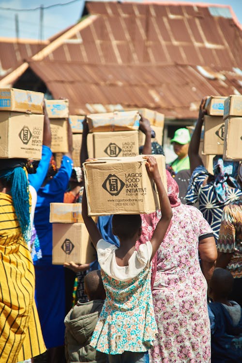 People Walking and Carrying Boxed on Their Heads