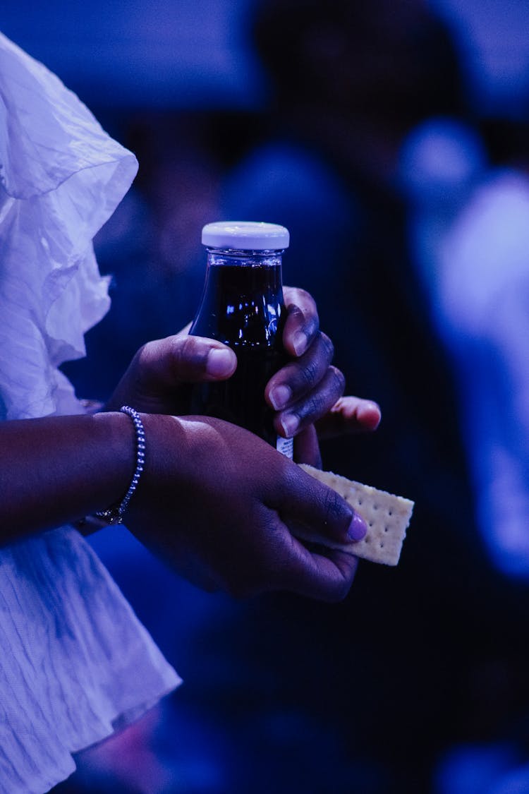 Person Holding Cracker Biscuit And Juice Bottle