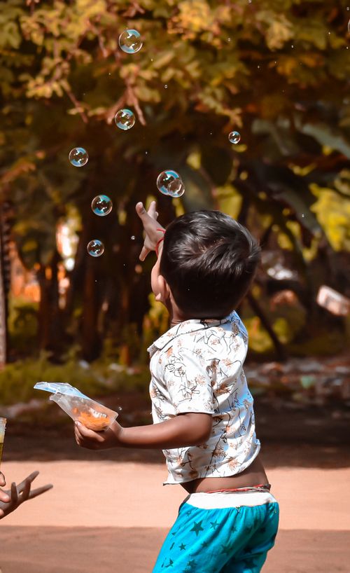 Free A child joyfully plays with bubbles in an outdoor setting in Peravurani, India. Stock Photo