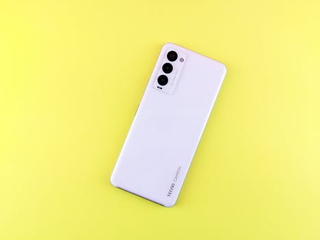 White smartphone with triple camera on a vibrant yellow background, emphasizing modern technology.