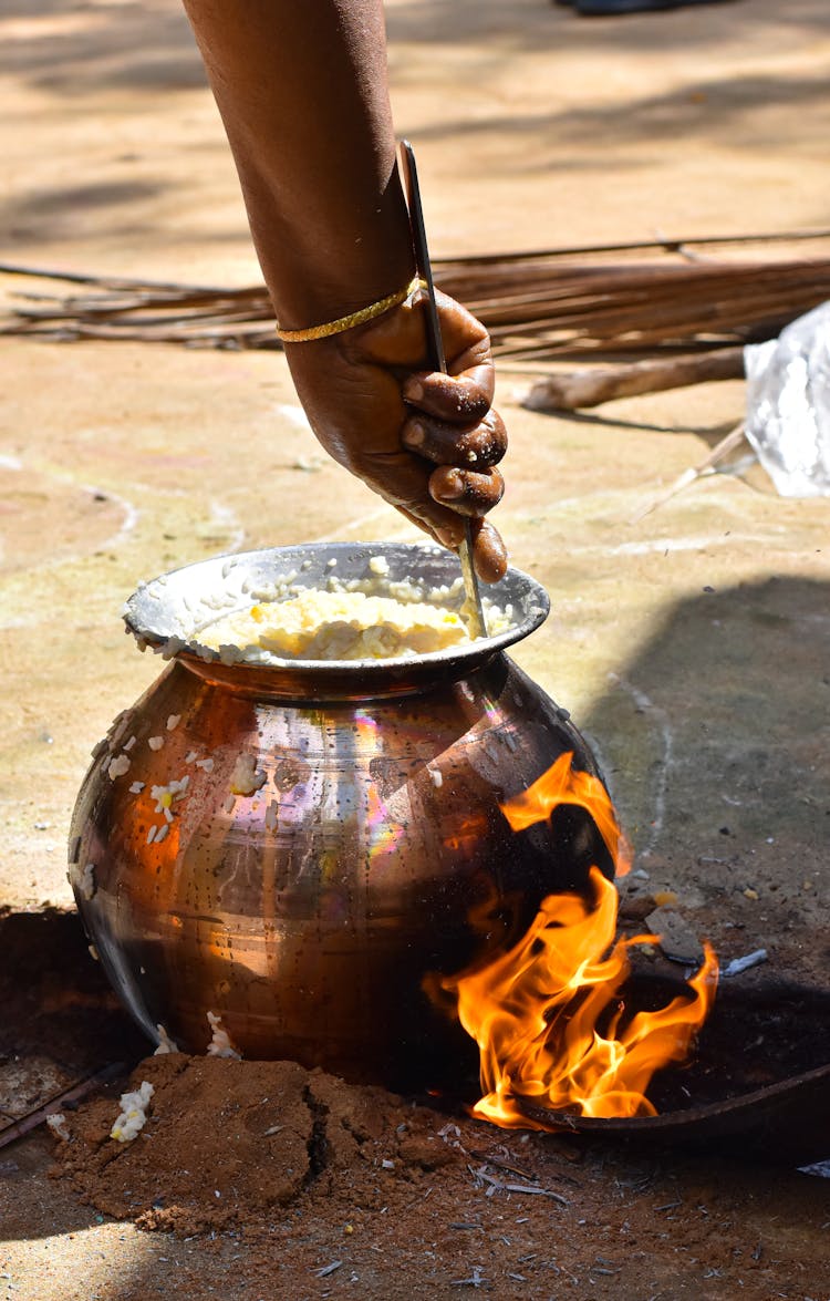 A Person Cooking In A Ceramic Pot With Fire