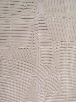 Closeup of a textured wall showing vertical adhesive lines in a home improvement context.