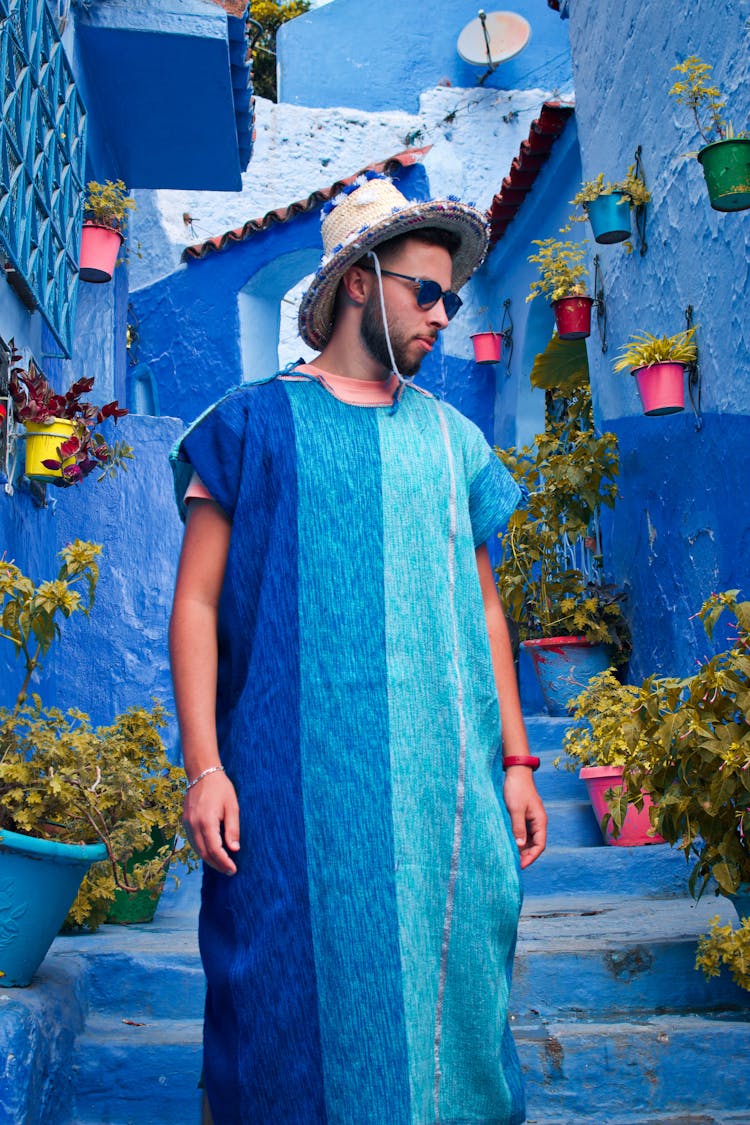 A Man Wearing Blue Djellaba Standing On Clue Painted Steps