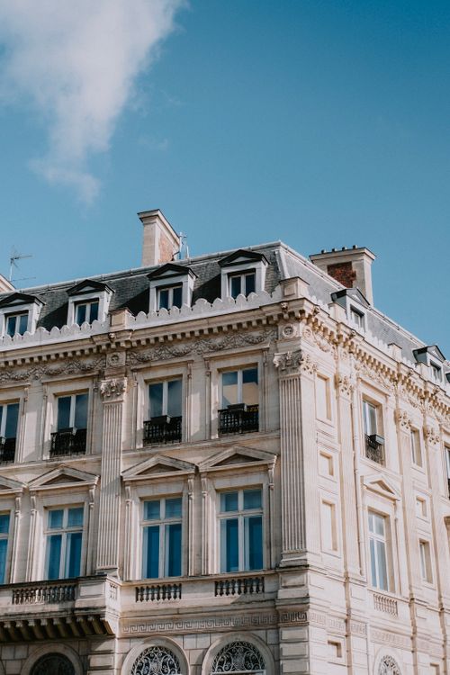 Free Elegant European-style building facade against a clear blue sky, showcasing architectural details. Stock Photo