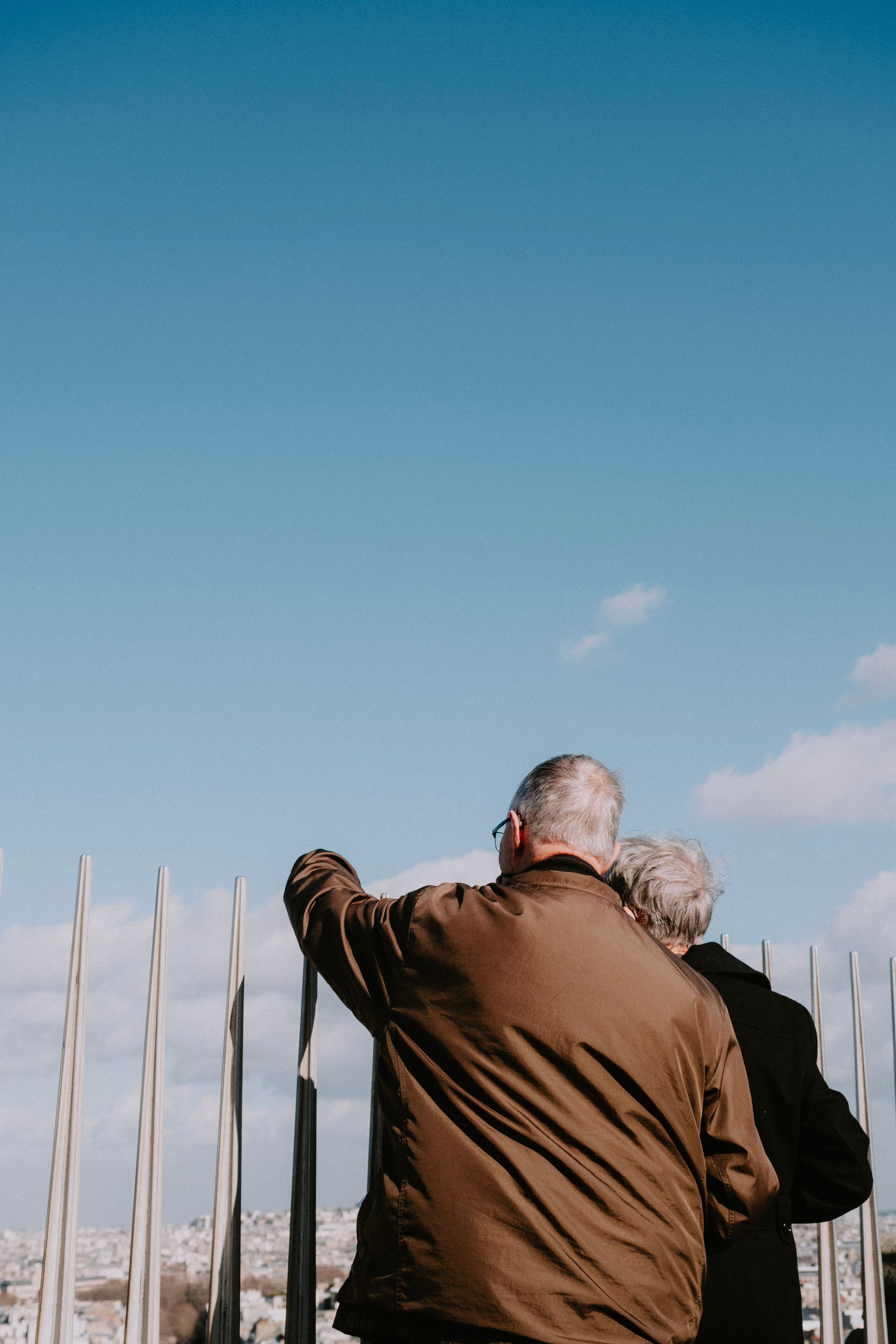 Elderly couple enjoying a scenic city view together, pointing at the skyline under a clear blue sky.