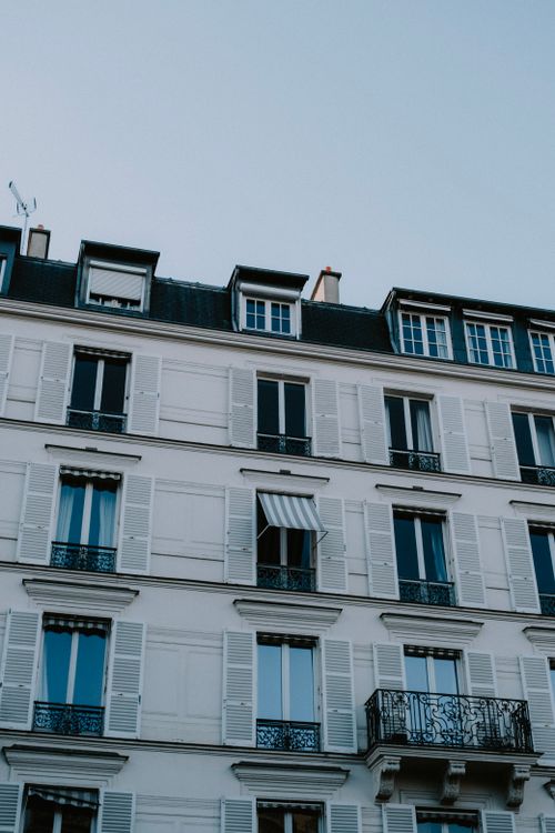 Free Close-up view of a classic Parisian building facade with white shutters and elegant balconies. Stock Photo