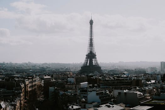 A stunning view of the Eiffel Tower rising above the Paris cityscape under a cloudy sky.
