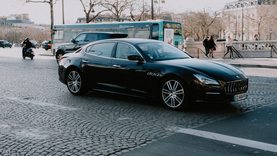 Une élégante voiture noire circulant dans une rue européenne en plein jour.