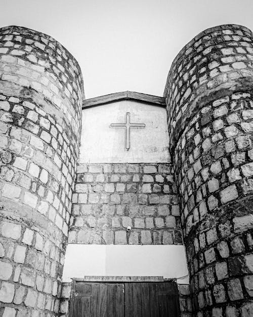 Grayscale Photo of Brick Building with Cross on Wall