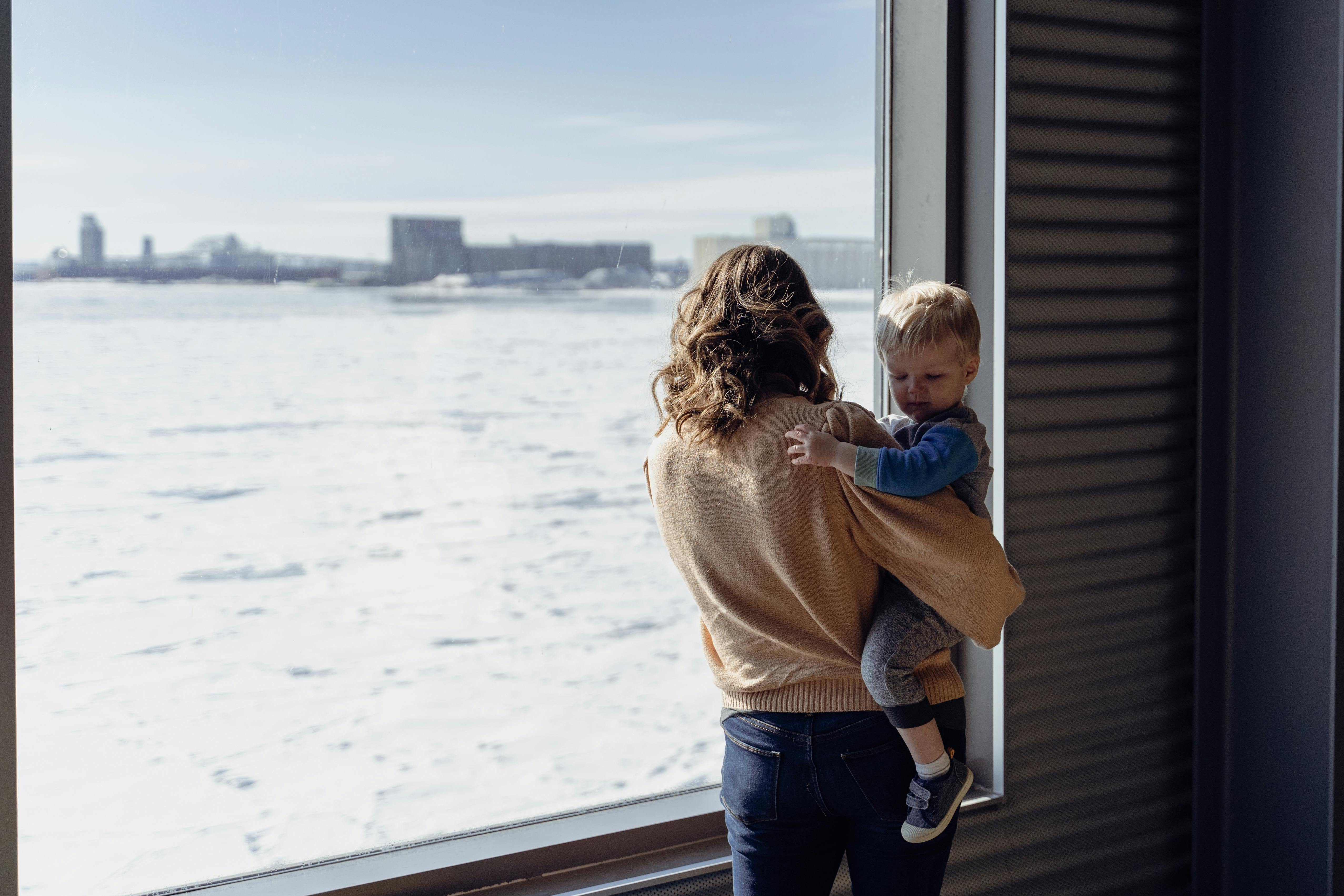 woman with child looking at sea through window