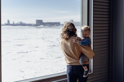 Free Woman with Child Looking at Sea through Window Stock Photo