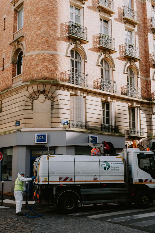 Free Street cleaning truck and worker in historic European street. Stock Photo