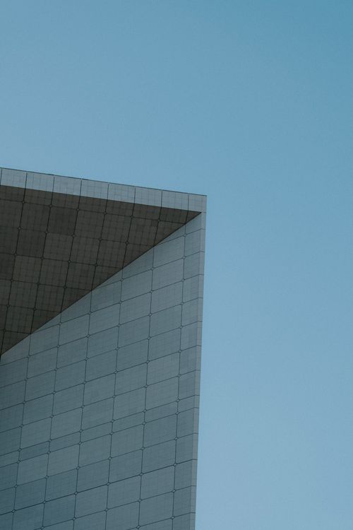 Free A minimalist view of a modern building corner with a clear blue sky backdrop, showcasing urban architecture. Stock Photo