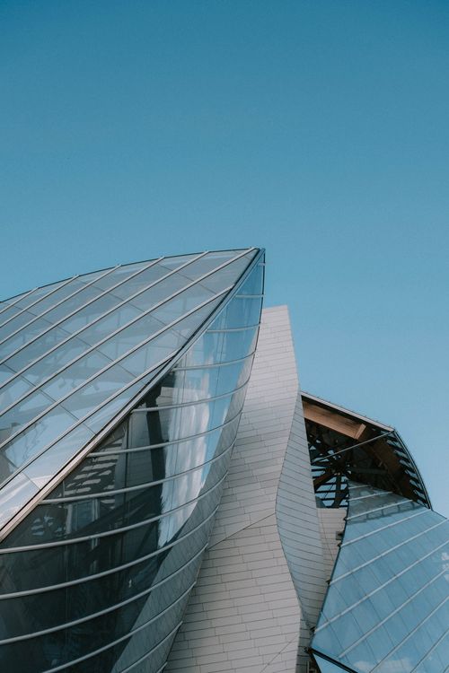 Free Sleek modern architecture with glass panels and clear sky. Perfect for urban and architectural themes. Stock Photo