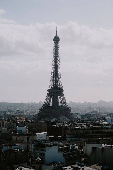 Stunning drone shot of the Eiffel Tower against the Parisian skyline on a cloudy day.