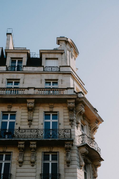 Free Charming French-style residential building facade with ornate balconies and classic design. Stock Photo