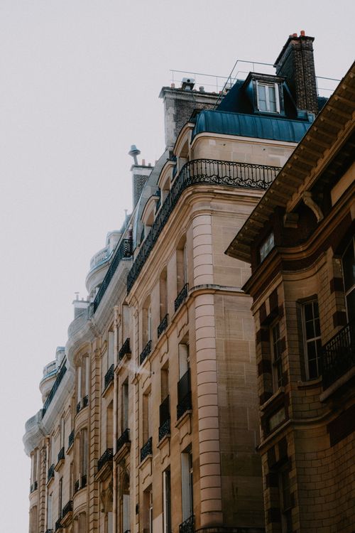 Free Low-angle view of classic Parisian townhouses with ornate facades and balconies in soft light. Stock Photo