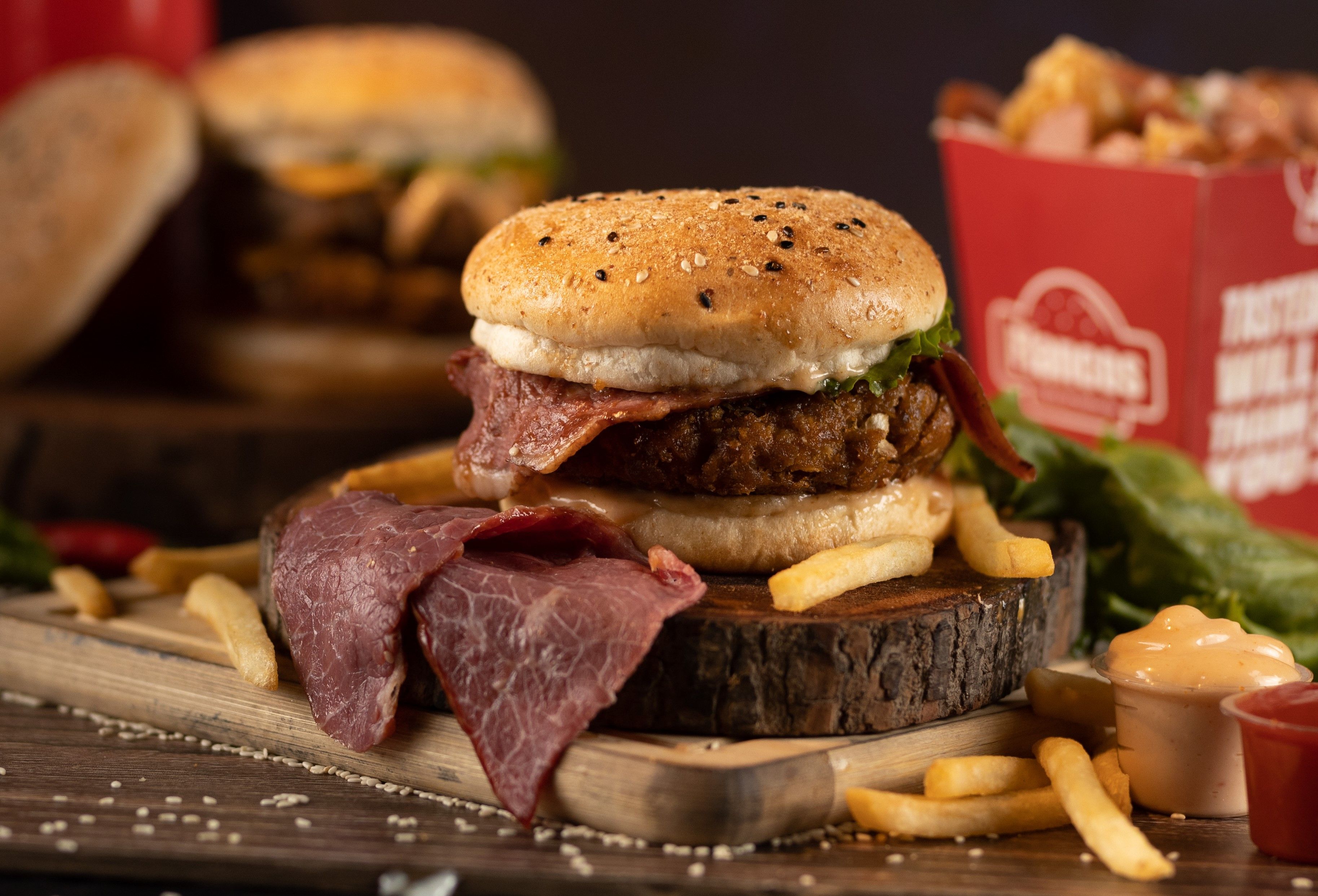 Delicious gourmet burger with fries and sauce on a rustic wooden plate, perfect for food lovers.