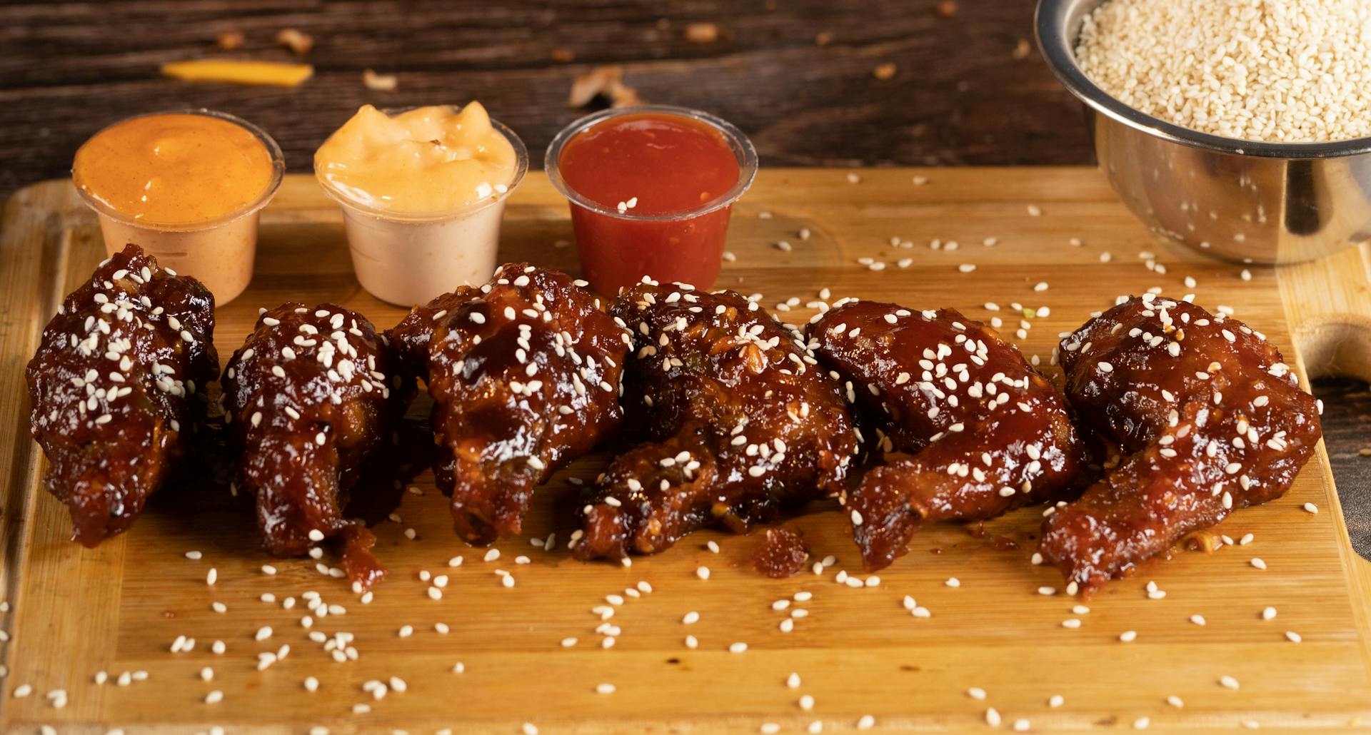 Buffalo Wings with Sesame Seeds and Dips on Plastic Containers