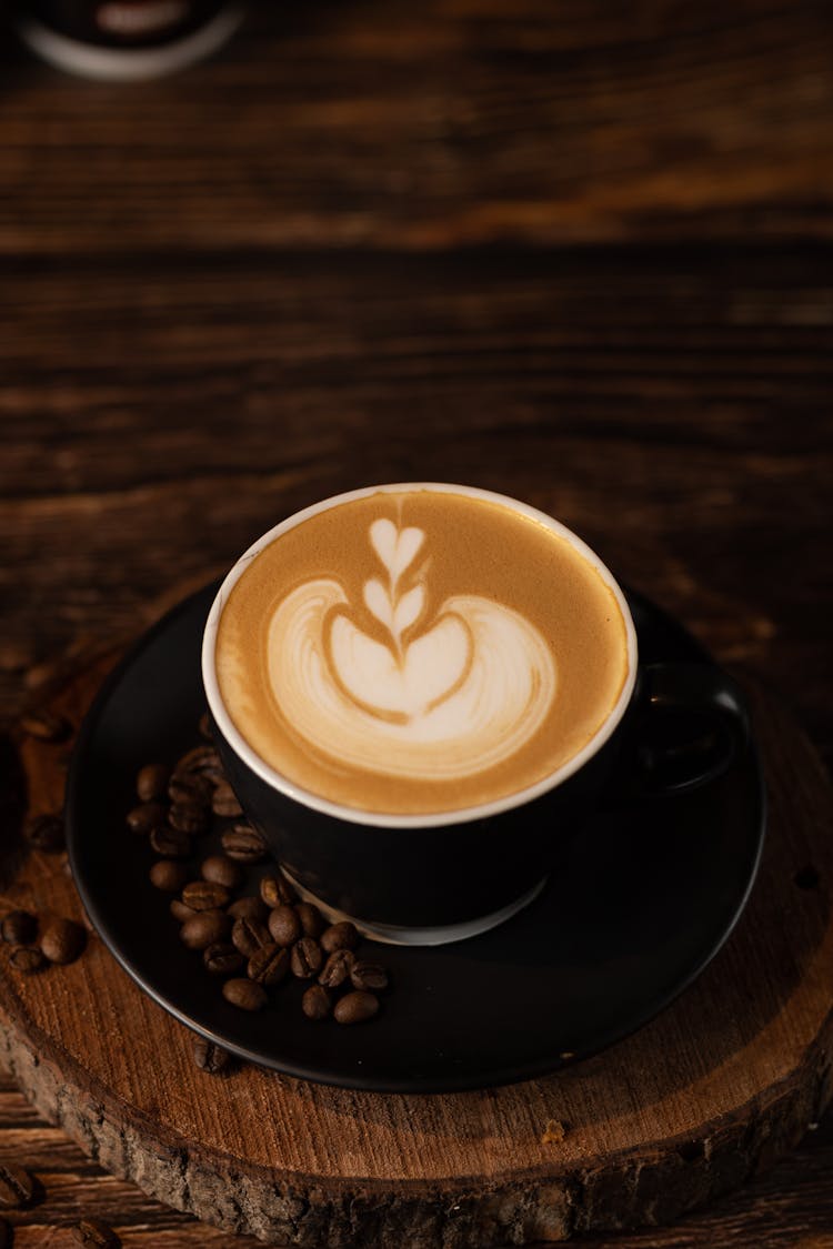 A Cup Of Coffee With Heart Latte Art In A Black Cup And Saucer