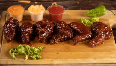 Barbecue chicken wings on a wooden board, photo by Meraj Kazi on Pexels