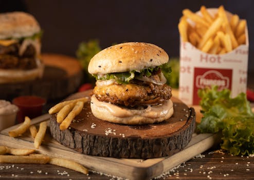 Juicy burger with lettuce and crispy fries on a wooden board, perfect for fast food lovers.