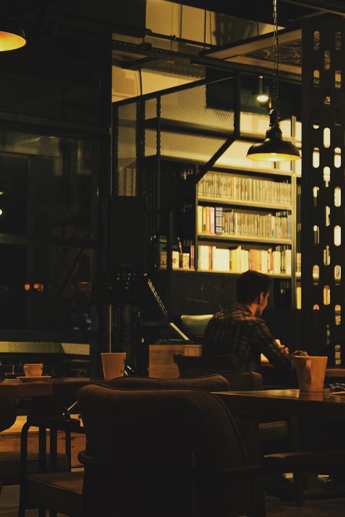 Free Warm ambiance of a café interior with a man sitting alone, enjoying the serene environment. Stock Photo