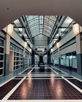 A spacious, modern mall atrium with a striking skylight ceiling, showcasing architectural symmetry.