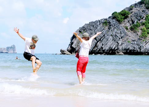 两个人在热带海滩愉快地度过了一天，那里有清澈的蓝色海水和岩石悬崖