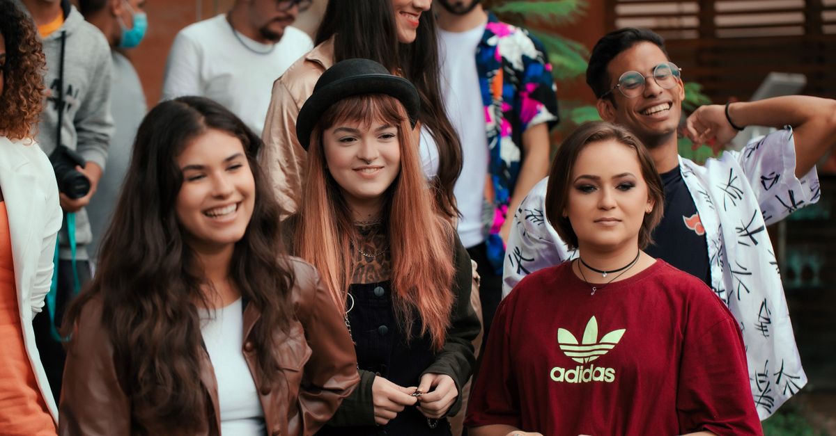 Gen Z friends laughing while wearing mismatched thrift store outfits and Crocs in a city park