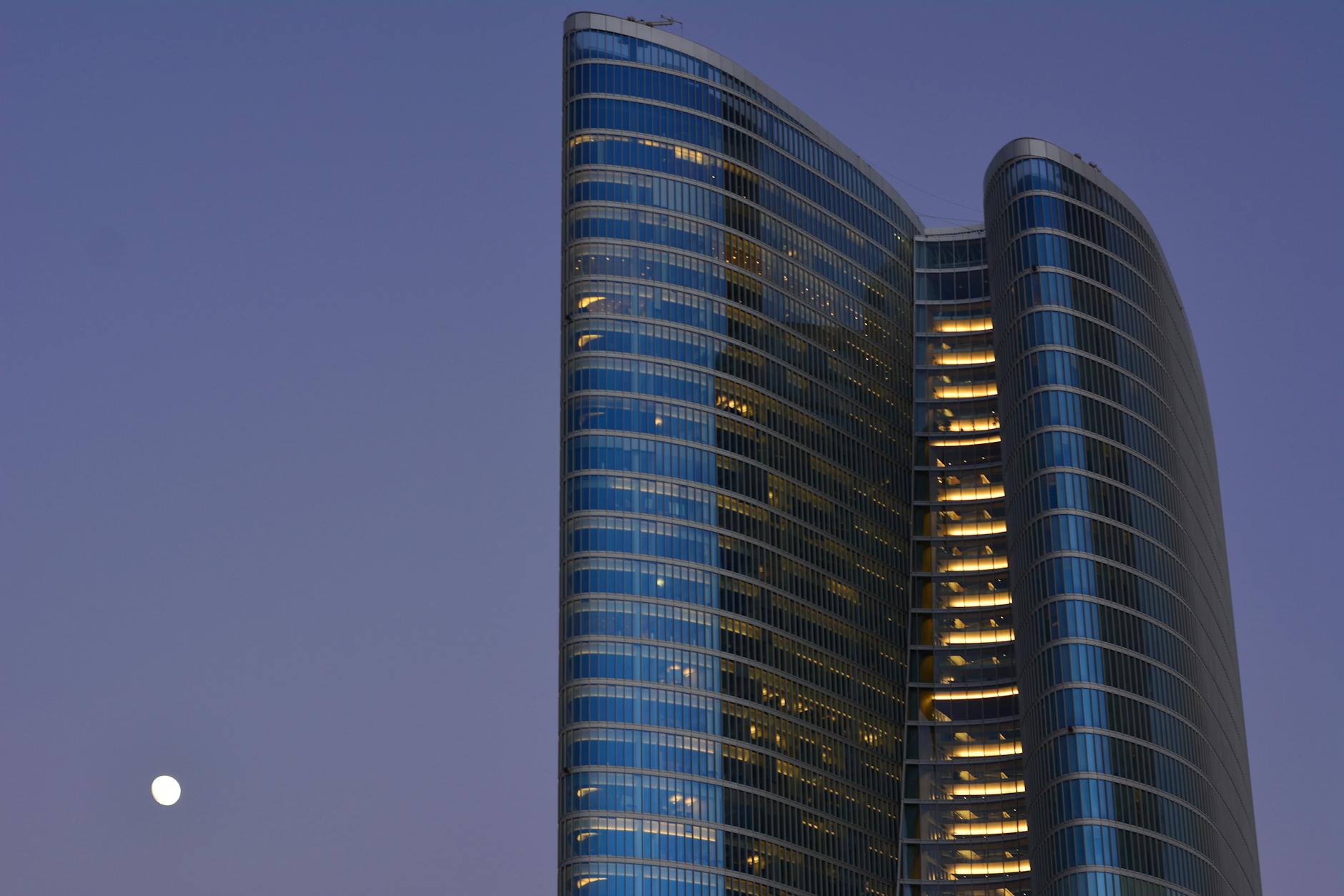 A striking modern skyscraper in Abu Dhabi with a moonlit sky enhances its architectural elegance.