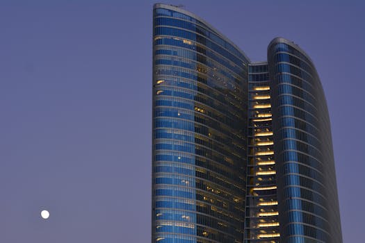 A striking modern skyscraper in Abu Dhabi with a moonlit sky enhances its architectural elegance.