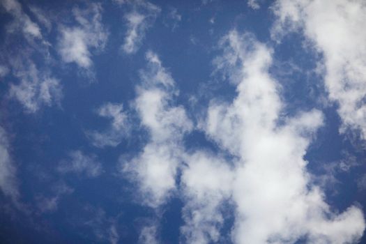 A tranquil view of a clear blue sky dotted with soft, fluffy white clouds.
