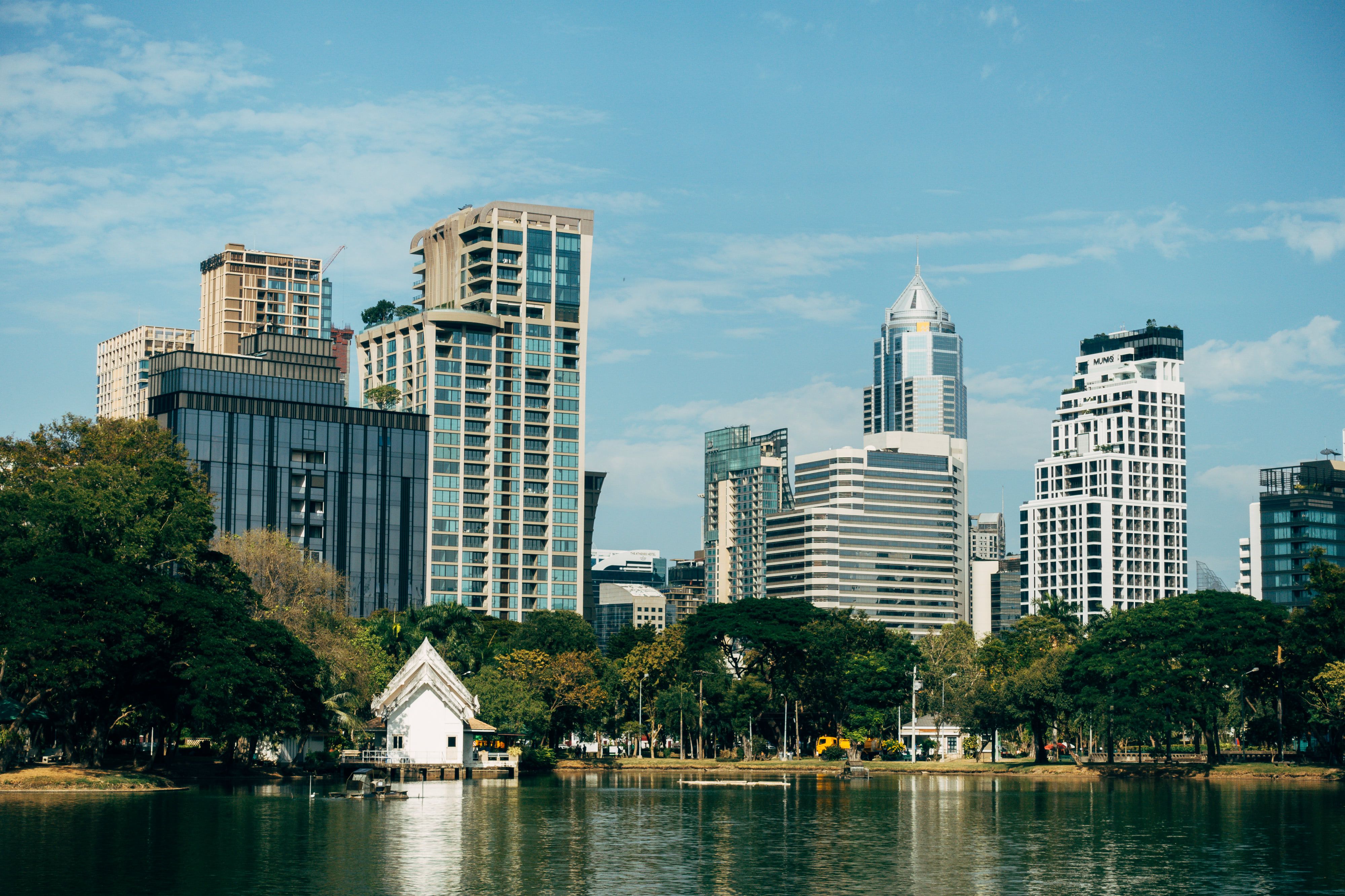 Vue imprenable sur la skyline de Bangkok avec le parc Lumphini et son lac, mettant en valeur la nature et l’architecture.