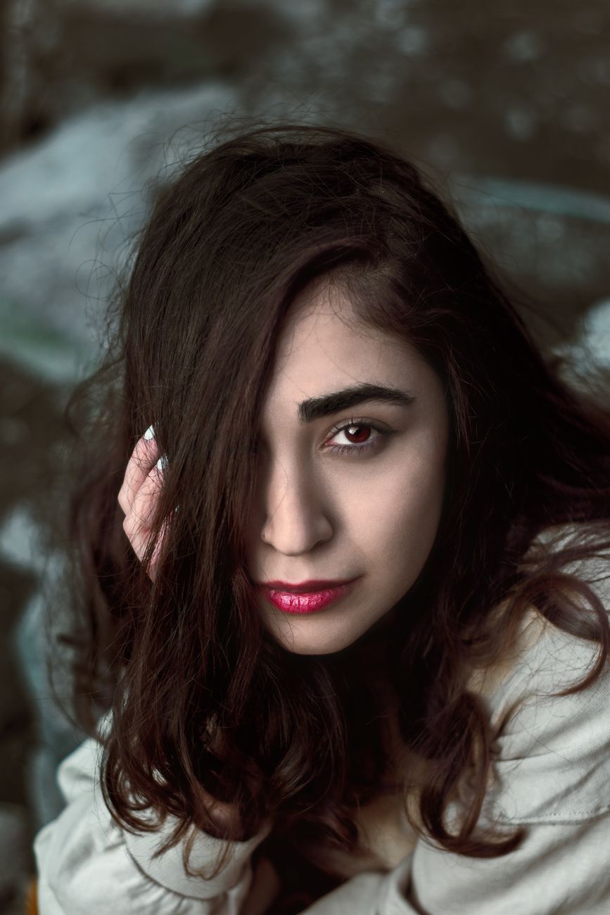 Close-up portrait capturing the elegance of a brunette woman with striking red lips and captivating gaze.