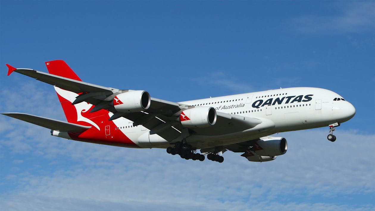 免費 白色和紅色的澳航飛機飛得很高，在藍色和白色的雲層下 圖庫相片