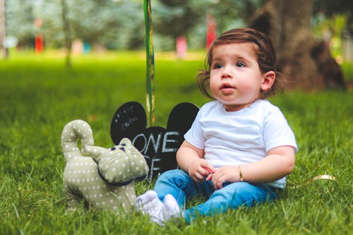 Фотография ребенка, сидящего на зеленой траве с глубиной резкости