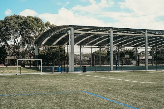 A versatile sports facility featuring a roofed court and soccer field under a bright sky.